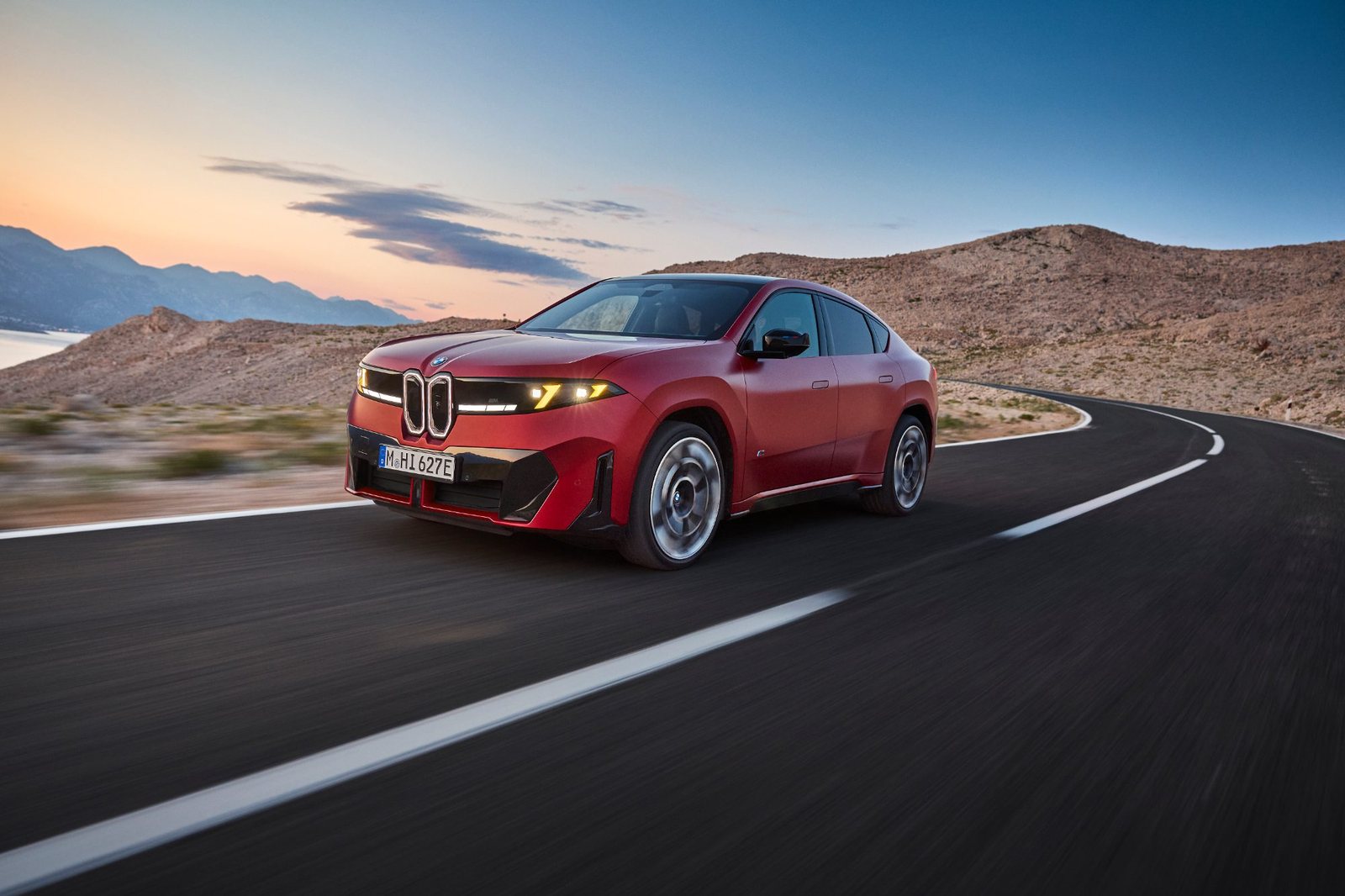 BMW iX4 M60 xDrive in Rot auf einer Küstenstraße